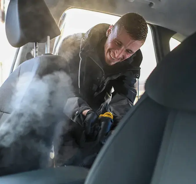 Tehnician care curăță interiorul unei mașini cu aparat profesional de injecție-extracție